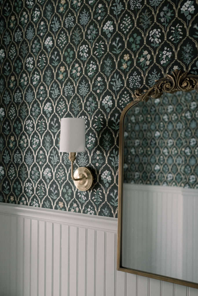 This dark marble bathroom is a stark contrast from what it was before – cramped and in need of work. The Rifle Paper Co Hawthorne wallpaper contrasts perfectly with all of the marble tile from The Tile Shop. The sconces from Signature Hardware, the antique brass mirror from Kate & Laurel, and the Farrow and Ball Purbeck Stone painted beadboard tie the whole space together.